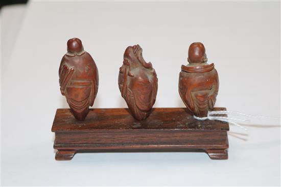 A set of six Chinese peach stones carved as immortals and a monkey, rosewood stands, each approx. height 4cm